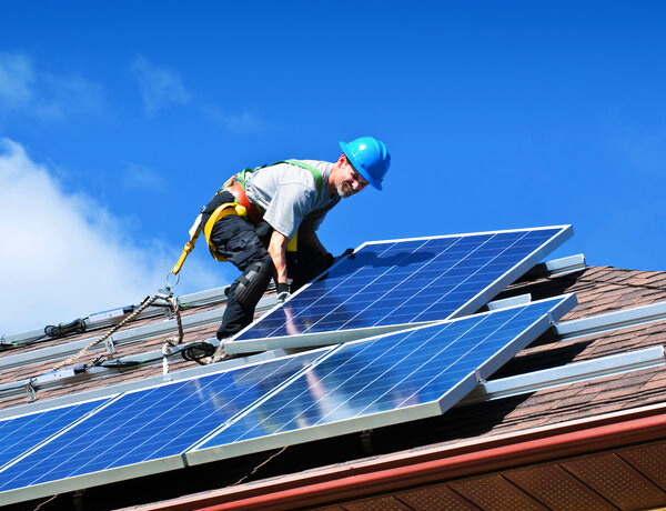 Fachkraft montiert Photovoltaikmodule auf einem geneigten Ziegeldach